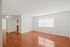 Bright, spacious apartment interior with gleaming hardwood floors, ample natural light, and a cozy kitchen area.