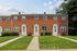 Charming townhouse with traditional red brick exterior, featuring well-maintained grassy lawns, inviting doorways, and picturesque windows.
