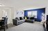 Bright and modern living room featuring a stylish gray sectional sofa, elegant wall art, and a vibrant blue accent wall.