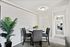 Modern apartment dining area with a stylish round table, upholstered chairs, and fresh yellow flowers. Bright hallway leading to a cozy bedroom creates a welcoming ambiance.
