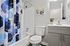Elegant bathroom featuring modern fixtures, a sleek vanity, and a stylish blue geometric shower curtain.
