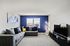 Inviting living room with a plush gray sectional sofa, accented by vibrant pillows and modern decor against a bold blue accent wall.