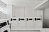 Modern apartment laundry room featuring a row of sleek white dryers and washers, highlighting convenience and style.