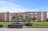 Charming brick apartment building with lush green landscaping and ample parking space, perfect for comfortable urban living.