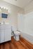 Elegant bathroom featuring modern fixtures, stylish vanity, and a pristine bathtub against warm wood flooring.