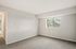 Bright, airy room with plush carpeting and large window overlooking greenery, perfect for a cozy bedroom or office space.