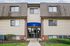 Charming apartment building entrance with a welcoming blue canopy, manicured landscaping, and modern design.