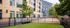 Modern apartment building with a stylish fenced courtyard, lush greenery, and inviting bench seating for relaxation.