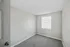 Bright minimalist bedroom with plush carpet and large window offering ample natural light.