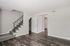 Inviting modern living area with elegant dark wood flooring, sleek staircase, and ample natural light.