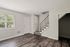 Bright and elegant living space featuring modern flooring, natural light from large windows, and an inviting staircase.