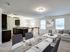 Inviting open-concept living and dining area with elegant dark cabinetry, chic decor, and abundant natural light.