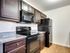 Modern kitchen with sleek dark wood cabinets, granite countertops, and stainless steel appliances for an elegant touch.
