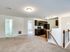 Inviting open-plan apartment with plush carpeted living area, elegant wooden staircase, and sleek kitchen featuring stylish dark cabinetry.
