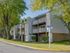 Charming apartment building with spacious balconies, nestled among lush green trees and well-maintained landscaping.