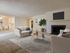 Inviting open-concept living room with plush seating, modern fireplace, and elegant decor, flowing into a brightly lit dining area and kitchen, perfect for entertaining.
