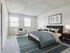 Inviting bedroom with natural light through two windows, featuring a cozy armchair, elegant wooden bed with plush bedding, and stylish decor for a serene retreat.