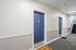 Inviting apartment hallway with vibrant blue doors and a welcome mat, offering a warm entrance to your new home.