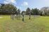 Charming green park at the Reserve at Sawmill with fenced dog park, benches, lush trees, and clear blue sky.