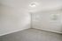 Bright and inviting empty room with soft carpet, natural light pouring through two windows, and sleek neutral walls.