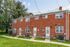 Charming brick townhouse exteriors with lush green lawns and a serene neighborhood setting.