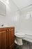 Modern bathroom with sleek white fixtures, rich wooden vanity, and bright lighting.
