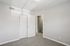 Bright, airy room with elegant carpet flooring and a sleek white double-door closet, perfect for a cozy bedroom or office space.