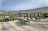 Charming residential outdoor space with modern patio furniture and a sleek barbecue grill, complemented by lush greenery and elegant building facade.
