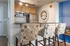 Chic kitchen space with stylish bar stools, sleek stainless steel appliances, and a modern wall clock, perfect for contemporary living.