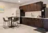Modern kitchen with sleek dark wood cabinets, stainless steel refrigerator, and cozy dining area with contemporary bar stools.