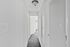 Bright and inviting hallway with soft carpet flooring and modern light fixture, leading to a spacious room in a stylish apartment.