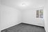 Bright, inviting room with plush gray carpet and a window offering natural light and a charming view.