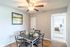 Charming dining area with modern decor, elegant ceiling fan, and natural light leading to a cozy bedroom retreat.