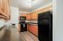 Modern Bilotta kitchen with black appliances, wooden cabinetry, and durable countertops for a warm, inviting cooking space.
