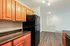 Modern Reserve at Sawmill kitchen with black appliances, wooden cabinetry, polished counters, and a bright living area.