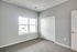 Bright and airy bedroom with large window and plush carpeting, offering ample natural light and cozy ambiance.