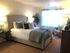 Inviting bedroom featuring a plush bed with stylish pillows, soft lighting, and a cozy seating area by a sunlit window.