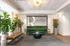 Elegant apartment lobby with green velvet sofa, modern lighting, and lush plants creating a welcoming ambiance.