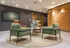 Modern lobby with green and brown chairs, stylish wall art, and warm lighting, creating a welcoming atmosphere.