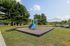 Inviting outdoor playground at the Reserve at Sawmill with blue slides, swings, lush trees, and open grassy spaces for families.