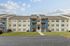 Modern three-story apartment at the Reserve at Sawmill with blue-beige exterior, balconies, green lawn, and spacious parking.