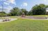 Inviting playground area with vibrant playset and swings, nestled in a lush green park setting with picnic tables and benches.