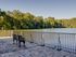 Scenic lakeside patio with elegant iron bench offering tranquil views and lush greenery, perfect for relaxation.