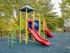 Vibrant community playground featuring colorful slides and climbing structures surrounded by lush greenery.