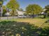 Charming community park featuring lush green grass, mature trees, and a secure fenced area, perfect for outdoor relaxation.