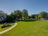 Inviting green space with well-maintained lawns, picnic benches, and a scenic walkway under a clear blue sky, perfect for relaxation.