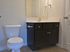 Modern bathroom with elegant dark wood vanity, polished sink, and a sleek toilet, offering a clean and inviting space.