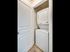Modern apartment laundry space featuring a sleek, white stacked washer and dryer set behind a partially open door.