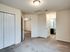 Inviting apartment interior with soft carpeted flooring, bright lighting, and convenient access to a modern bathroom.