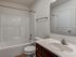 Modern bathroom with sleek fixtures, featuring a bright bathtub and a spacious vanity with a large mirror.